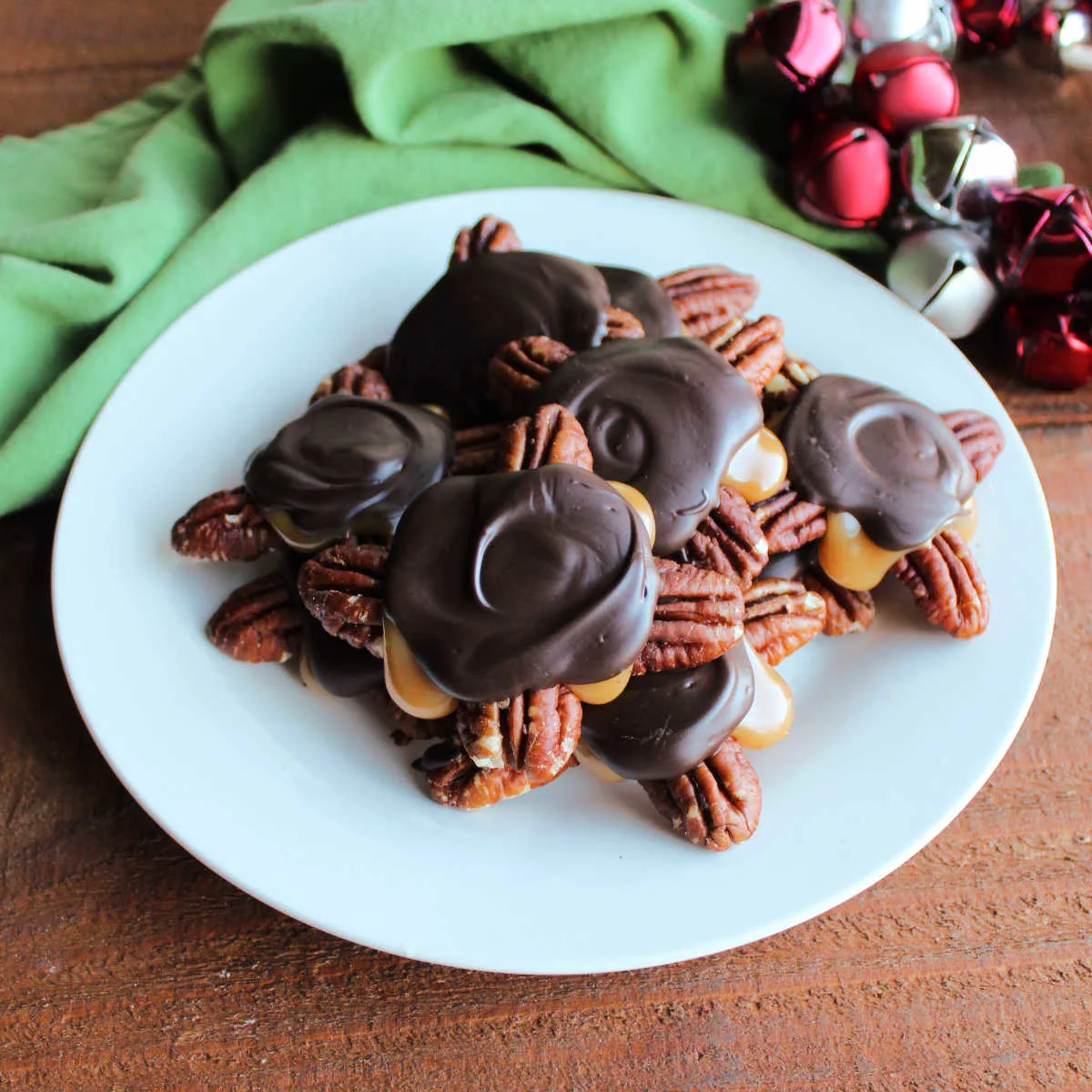 Plate of homemade turtles with pecans, soft homemade caramel, and dark chocolate.