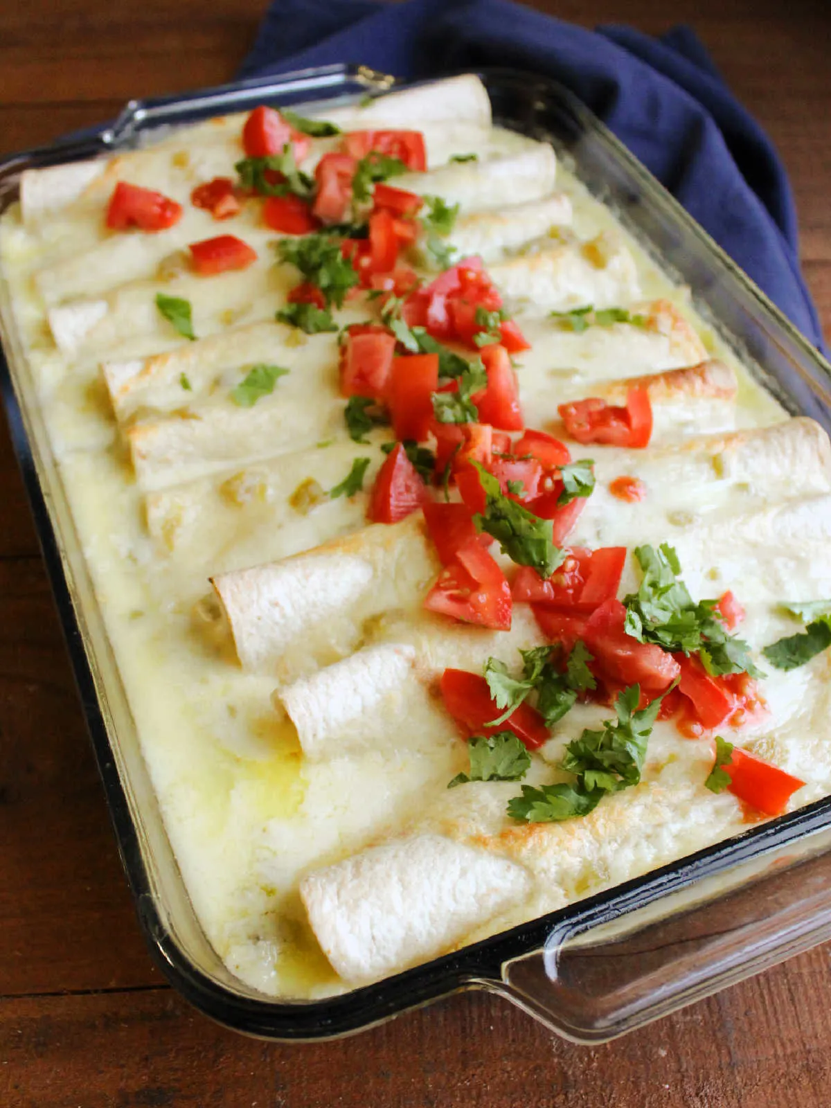 Pan of breakfast enchiladas topped with diced tomato and fresh cilantro, ready to be served.
