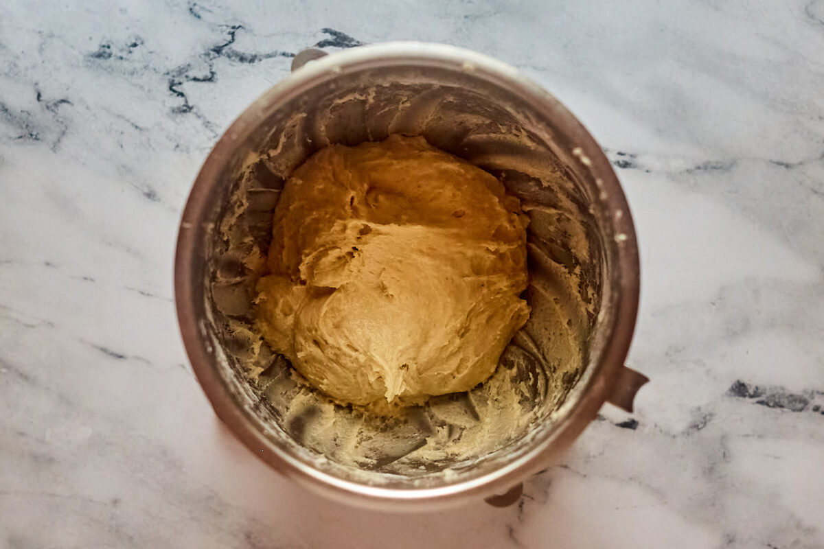 Kind of shaggy, soft cinnamon roll dough in mixer bowl.