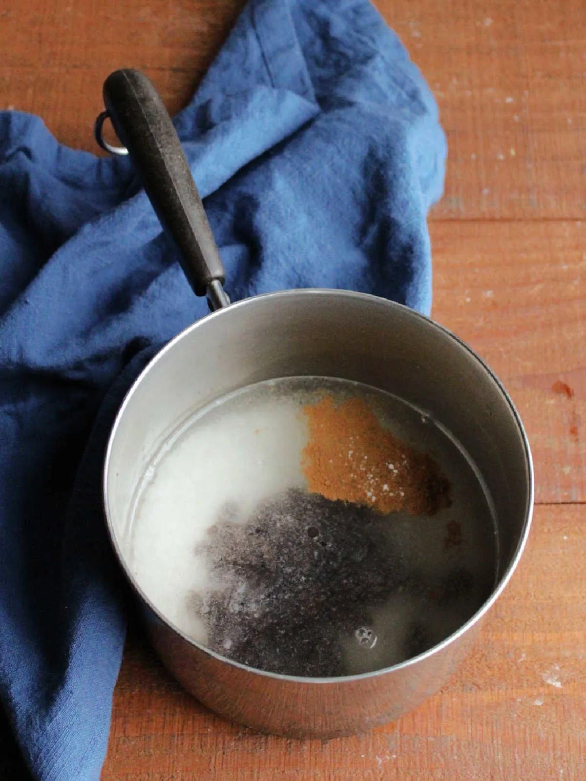 Rice, raisins, cinnamon, and salt soaking in water in saucepan.