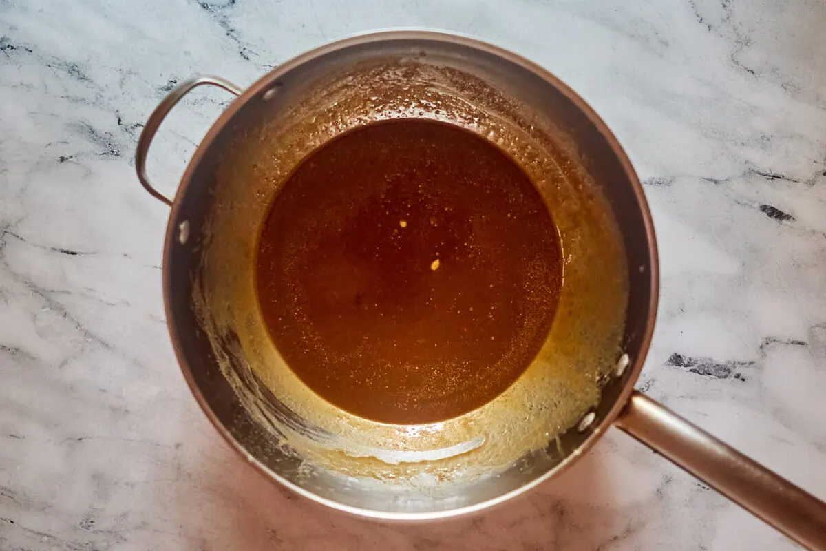 Saucepan with boiled milk, butter and brown sugar caramel mixture inside.