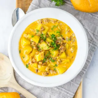 Bowl of creamy potato soup with Italian sausage garnished with parsley.