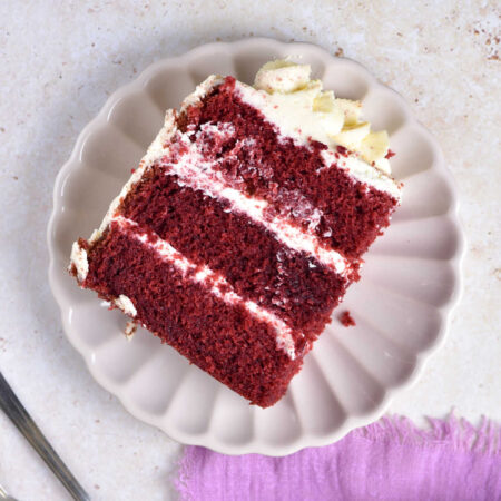 Red Velvet Cake 1 Piece of 3 layer red velvet cake with creamy frosting on plate, ready to eat.