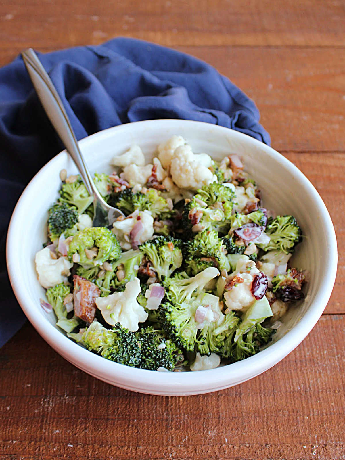 White bowl filled with homemade broccoli salad and fork, ready to eat. 