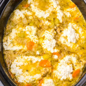 Crockpot Chicken and Dumplings 14 Fluffy steamed dumplings on top of chicken broth mixture in crockpot, ready to be stirred and served.