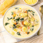 Bowl of creamy chicken soup with spinach, carrots, celery, and gnocchi ready to eat.