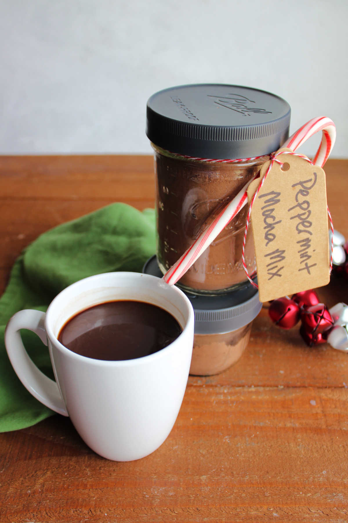 Mug of peppermint mocha next to two jars of the peppermint mocha mix. 