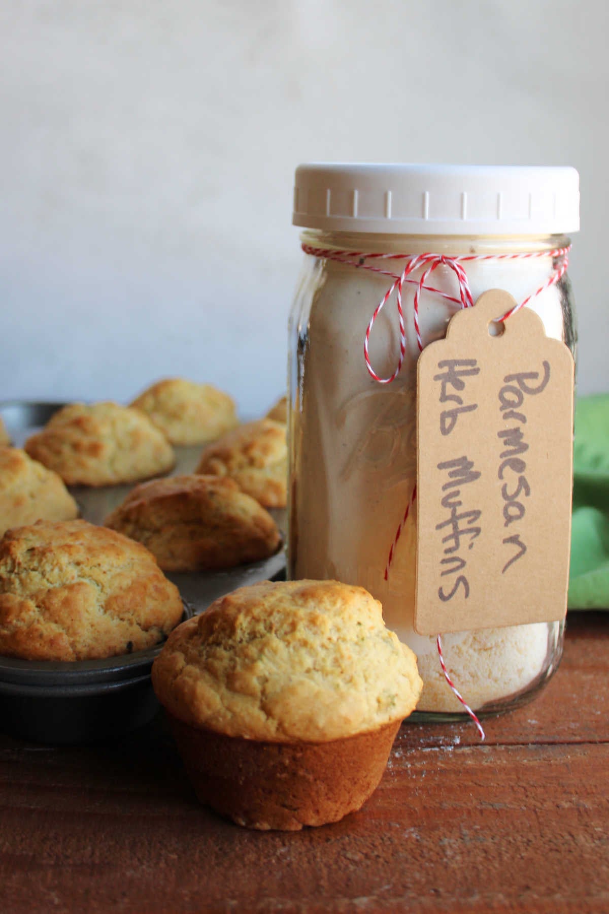 Jar of parmesan herb muffin mix next to a muffin tin of freshly baked savory muffins. 