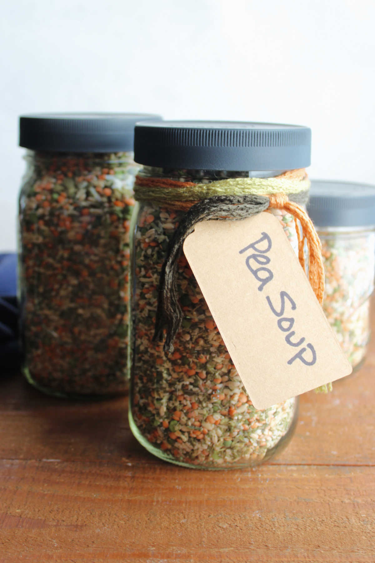 Two quart jars and one pint jar of homemade split pea soup with a tag saying what's inside and cooking instructions on it. 