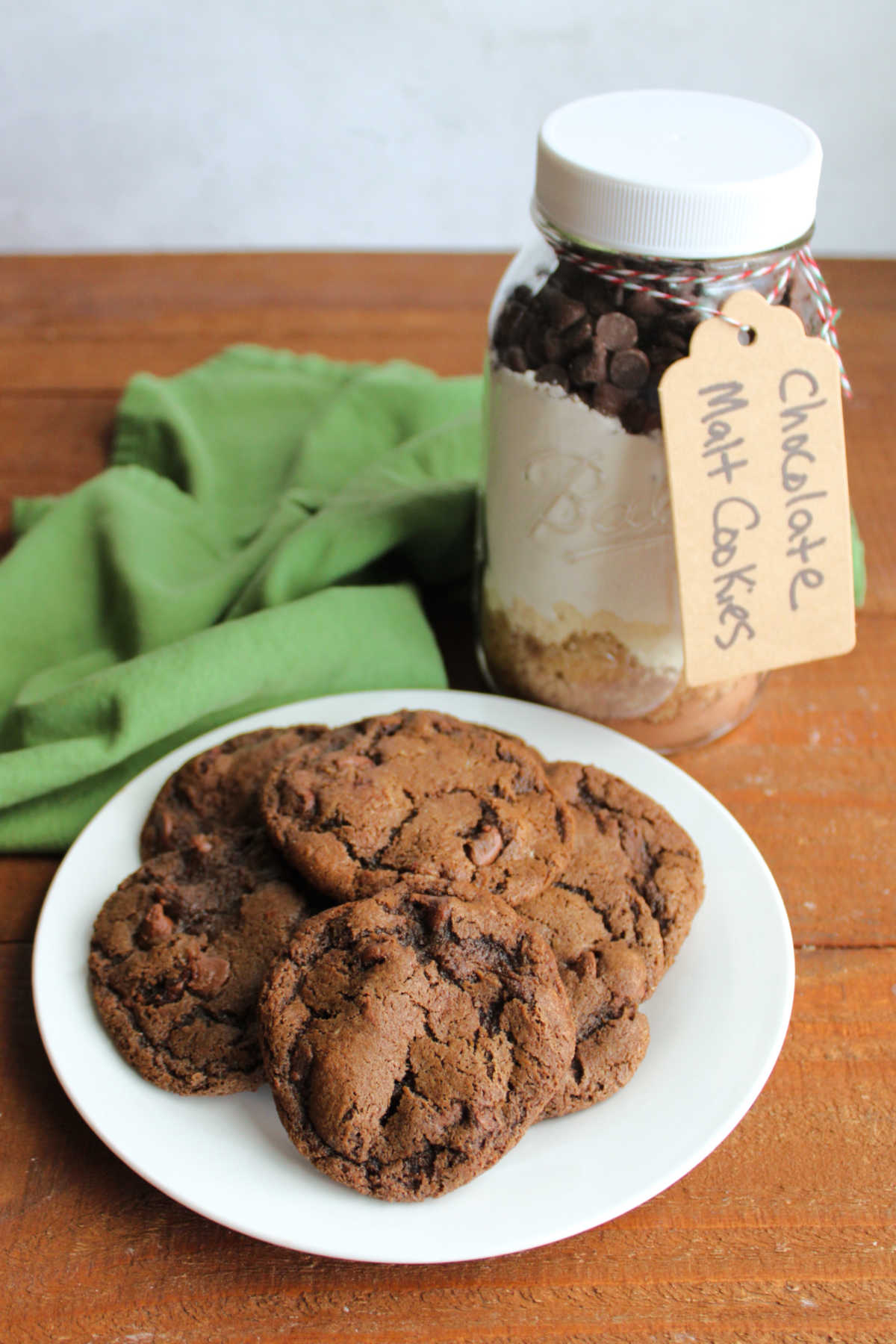 Jar of cookie mix next to a plate of freshly baked chocolate malt cookies. 