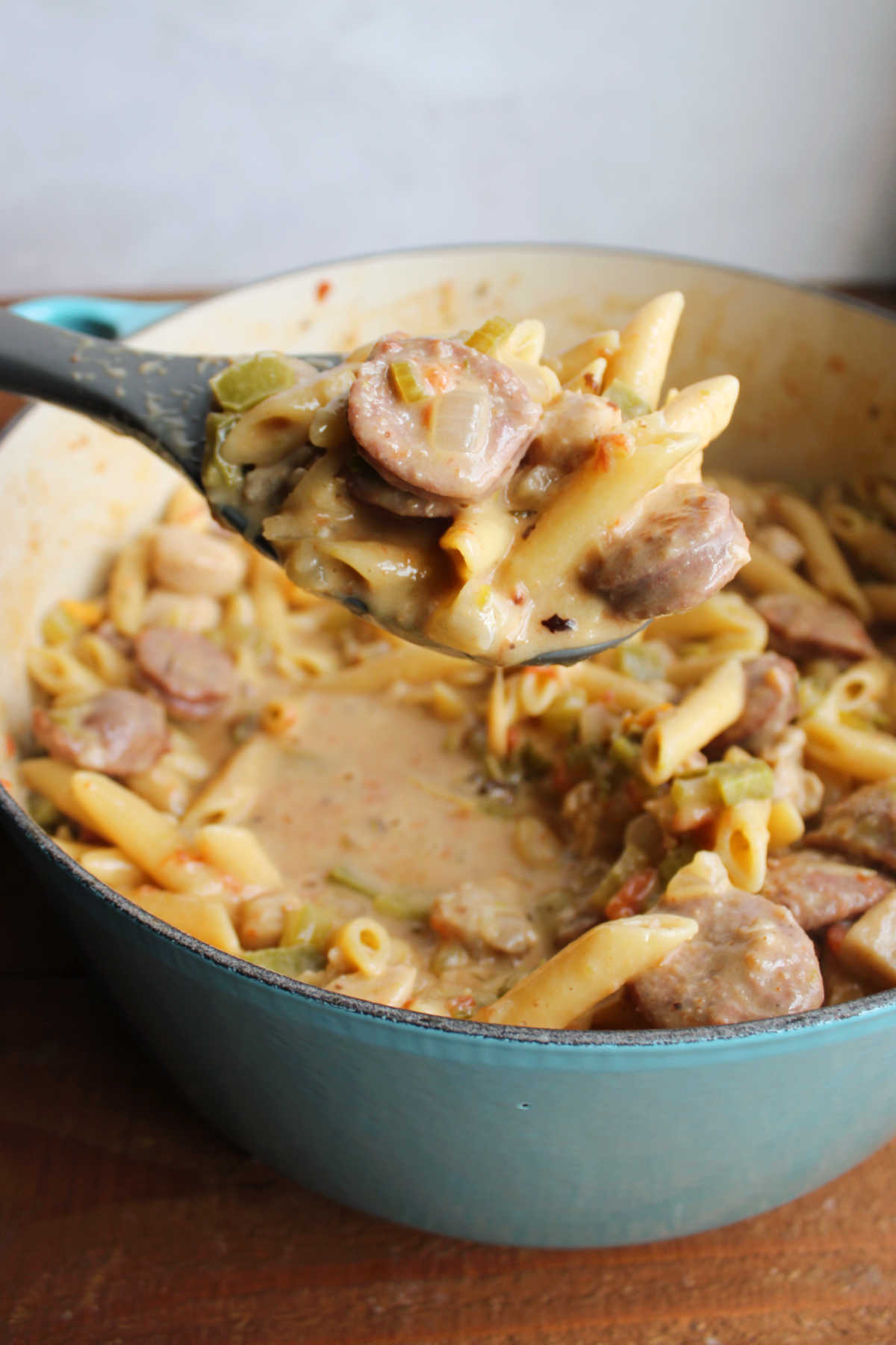 Serving spoon lifting a scoop of pastalaya out of the dutch oven showing pasta, sausage, chicken, and more. 