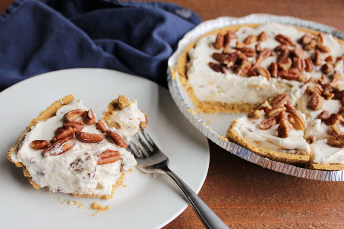 No Bake Pecan Cream Pie 9 Bite of pecan cream pie next to a slice of pie on a plate with remaining pie nearby.