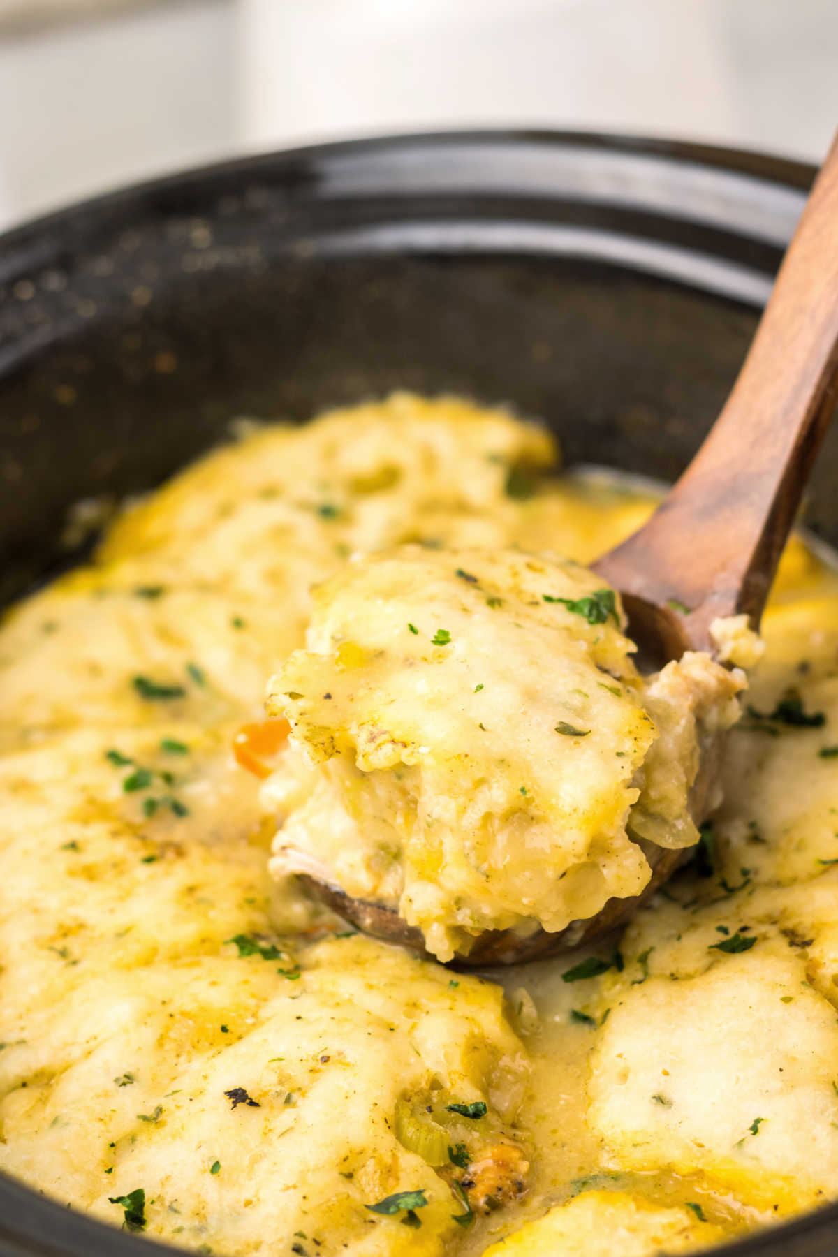 Crockpot Chicken and Dumplings 8 Serving spoon scooping out some chicken and dumplings out of the crockpot.