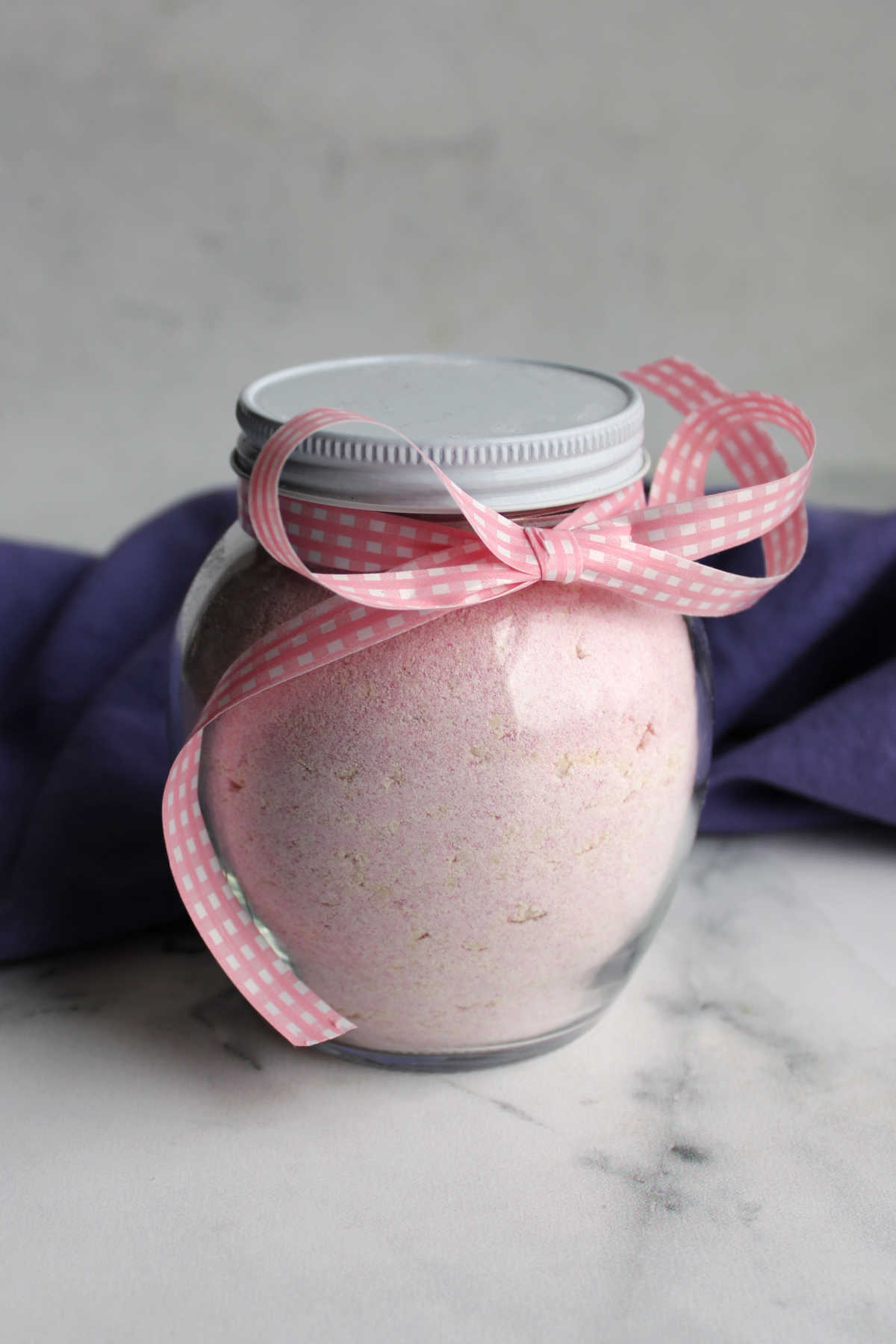 Jar of homemade strawberry hot chocolate mix showing pink powder inside. 