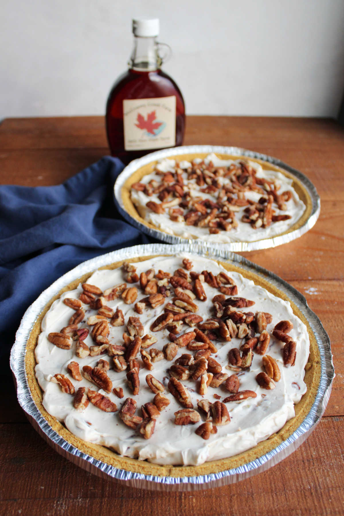 No Bake Pecan Cream Pie 10 Two whole pecan cream pies topped with toasted pecans with a bottle of maple syrup, ready to serve.