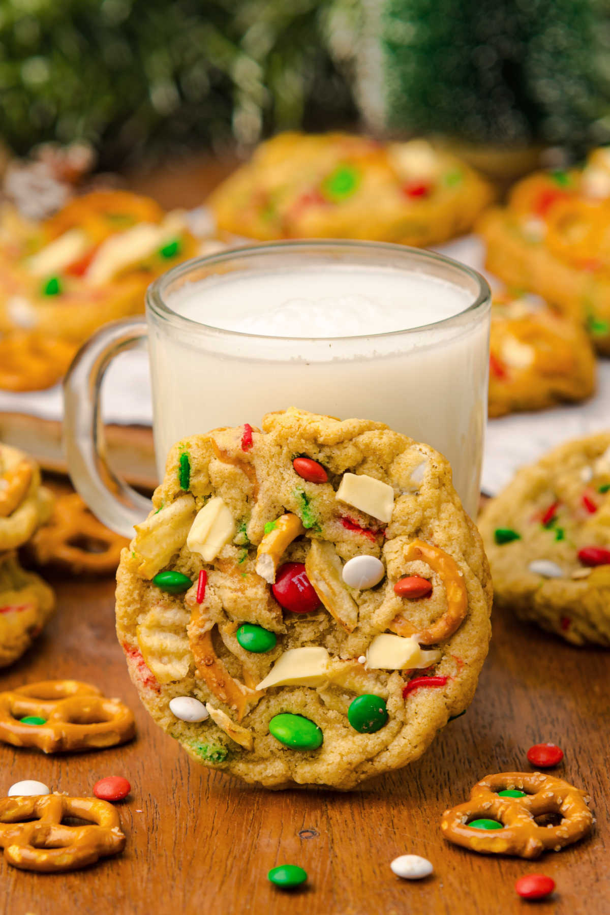 Christmas kitchen sink cookie leaned up against a mug of white hot chocolate, ready to enjoy. 
