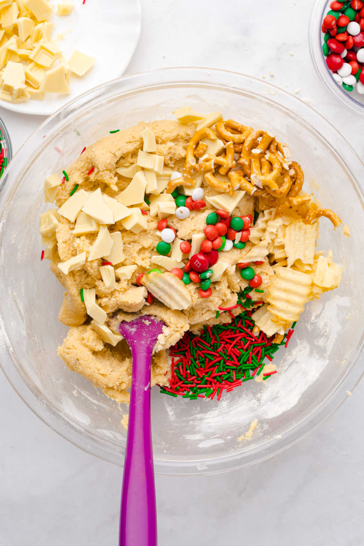 Stirring pretzels, potato chips, and candies into cookie dough in mixing bowl. 