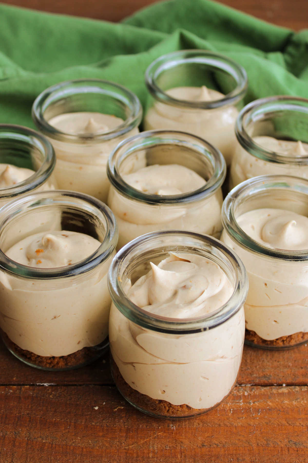 No Bake Biscoff Cheesecake Jars 9 Looking down on jars of no bake cookie butter cheesecake showing smooth fluffy texture with little bits of cookie throughout.