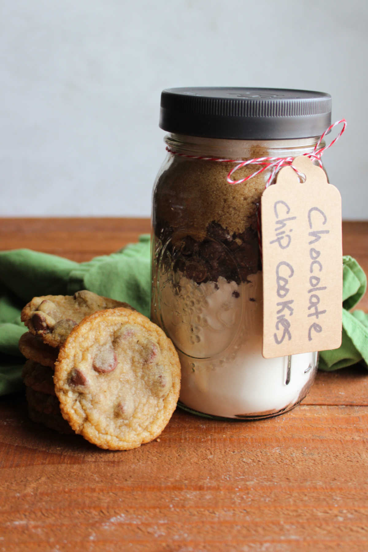 Jar of homemade chocolate chip cookie mix next to stack of cookies made from the mix. 