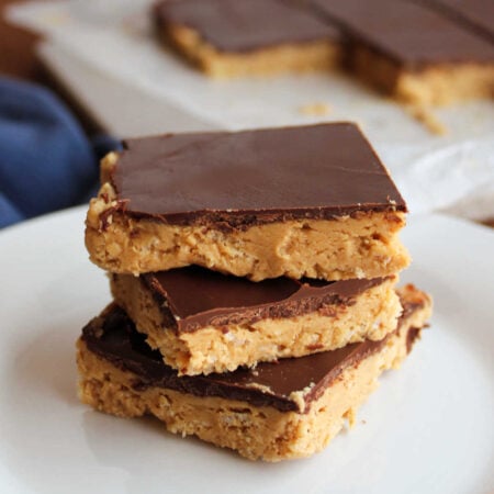 Crunchy Buckeye Bars With Rice Krispies 1 Stack of three buckeye bars with crunchy rice krispie and peanut butter layer on the bottom and a chocolate shell on top.