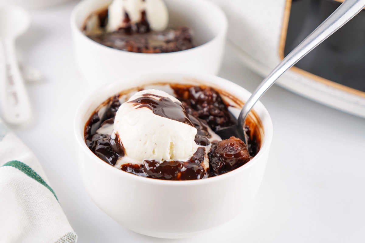 Crockpot Chocolate Cobbler 7 Close bowl of crockpot chocolate cobbler with scoop of ice cream and spoon, ready to eat.
