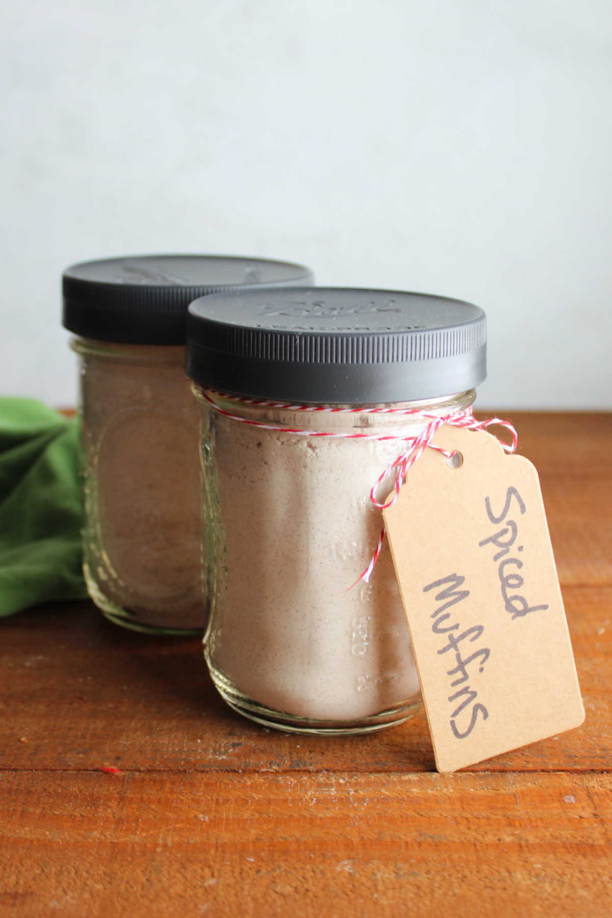 Two glass pint jars filled with homemade spiced muffin mix with a tag saying what is inside, ready to be given away as an edible gift. 