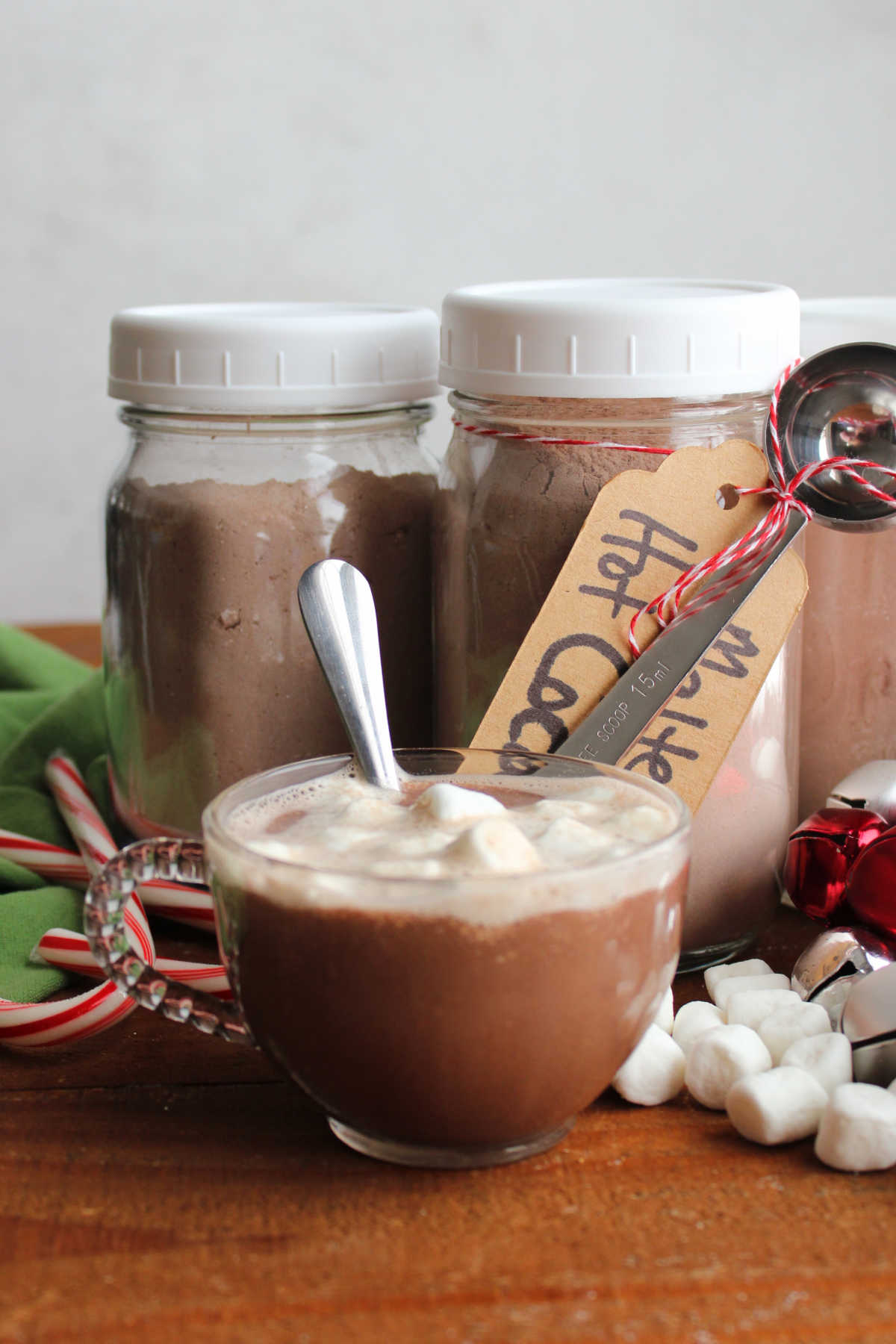 Mug of malted hot cocoa next to jars of homemade malted hot chocolate mix. 