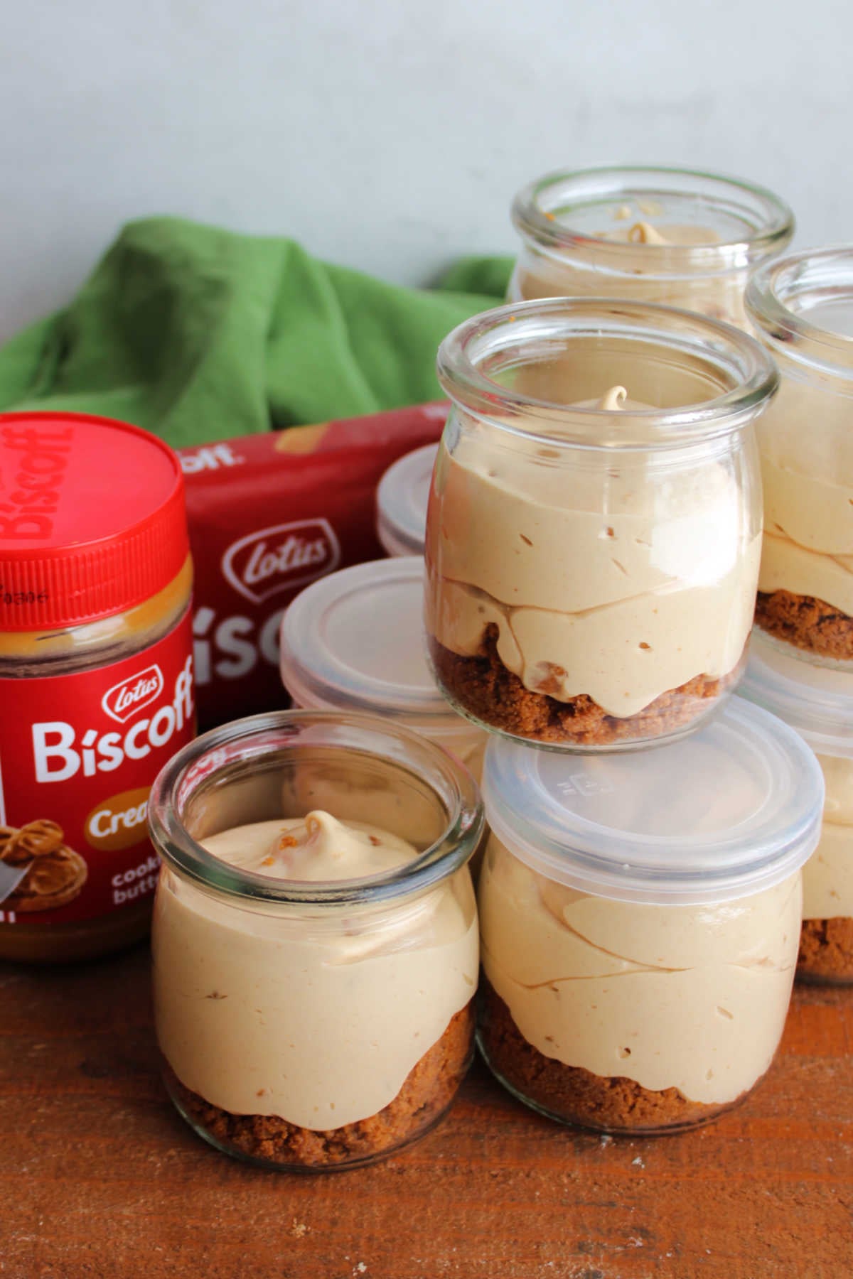 No Bake Biscoff Cheesecake Jars 8 Jars of no bake Biscoff cheesecake with a jar of cookie butter and some cookies in the background.