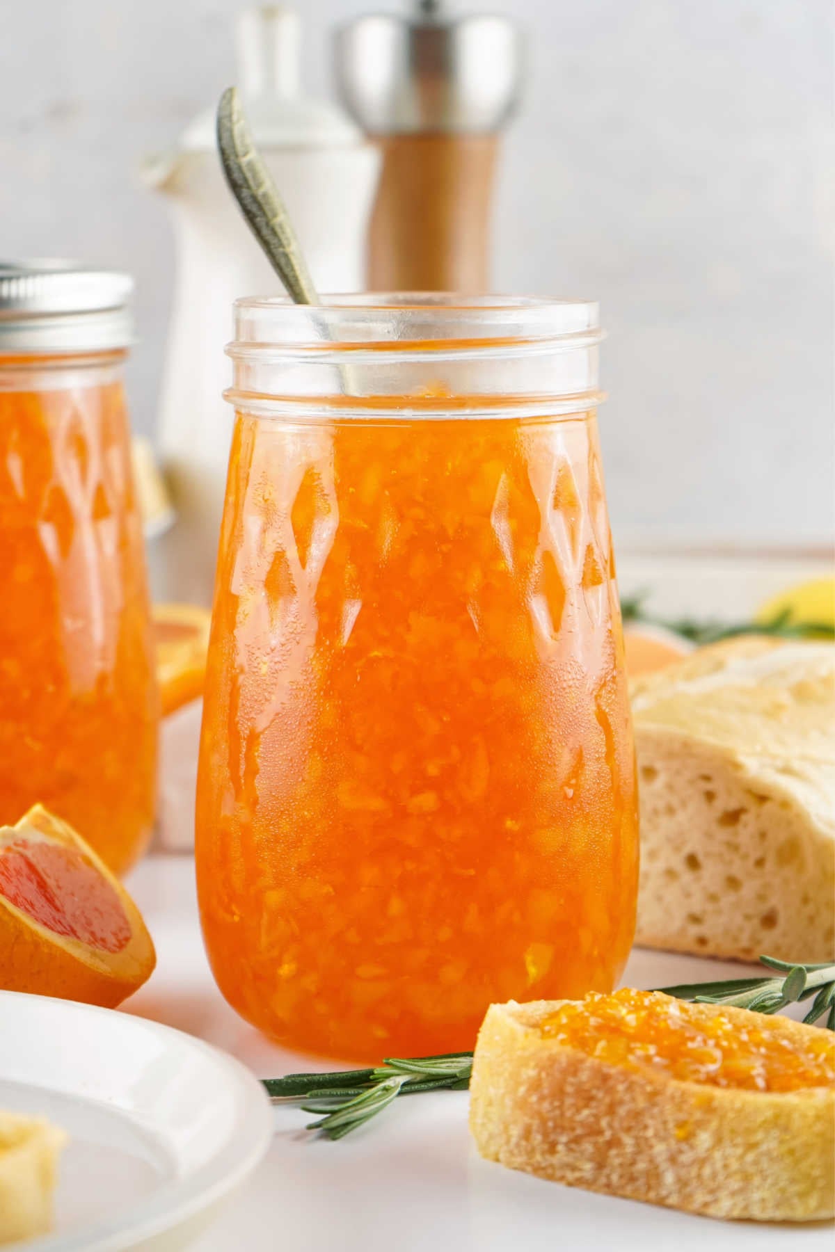 Jar of homemade orange marmalade next to a slice of toast with some spread over the top.