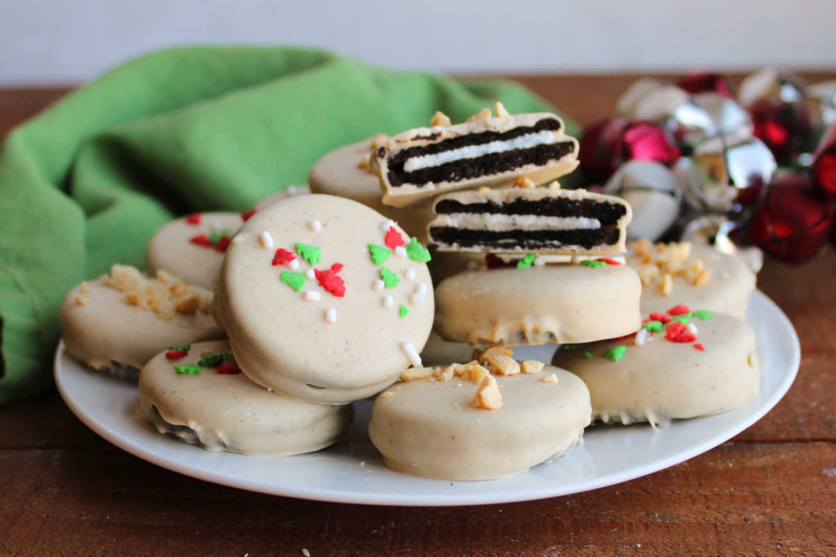 Plate of peanut butter dipped Oreos with creamy peanut butter coating topped with either sprinkles or chopped peanuts. 