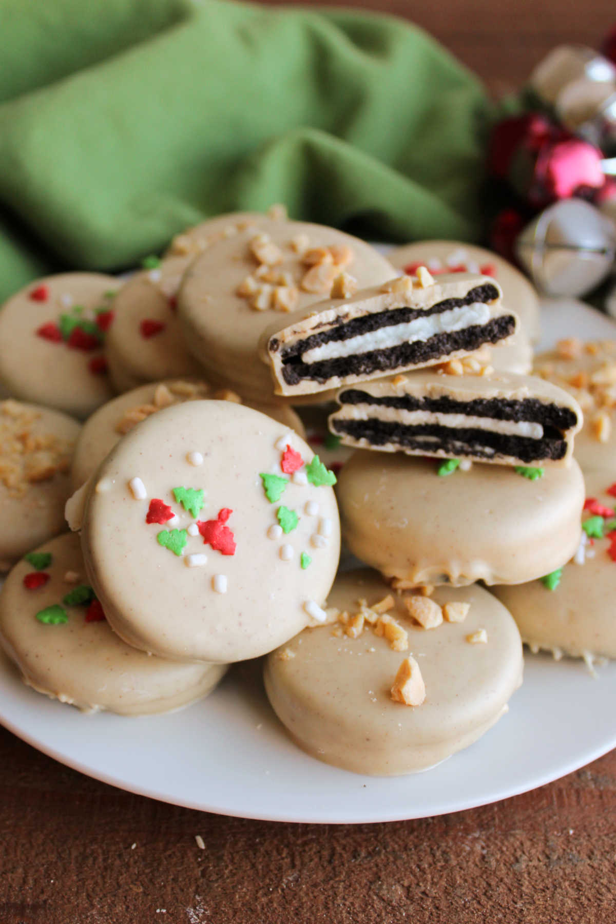 Plate of peanut butter dipped Oreso with one broken in half showing Oreo inside thin coating of white chocolate and peanut butter mixture. 