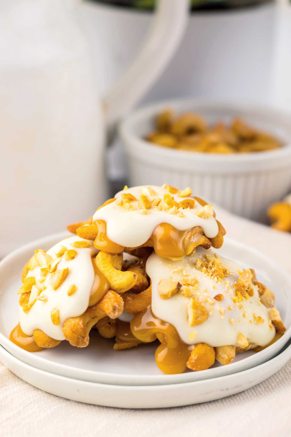 Pile of homemade white chocolate caramel cashew clusters on plate, ready to be served. 