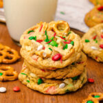 Stack of Christmas kitchen sink cookies with bits of pretzels, potato chips, white chocolate Christmas M&Ms, and sprinkles inside.