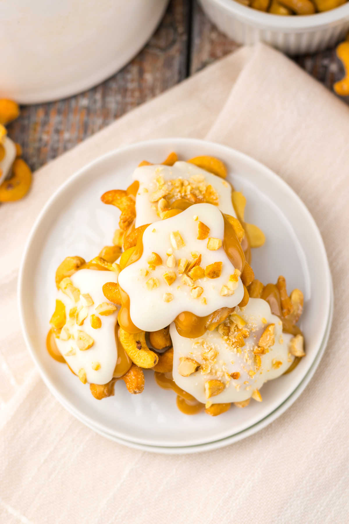 Looking down on a plate of homemade white chocolate caramel cashew clusters with edges caramel and nuts visible under white chocolate topping. 