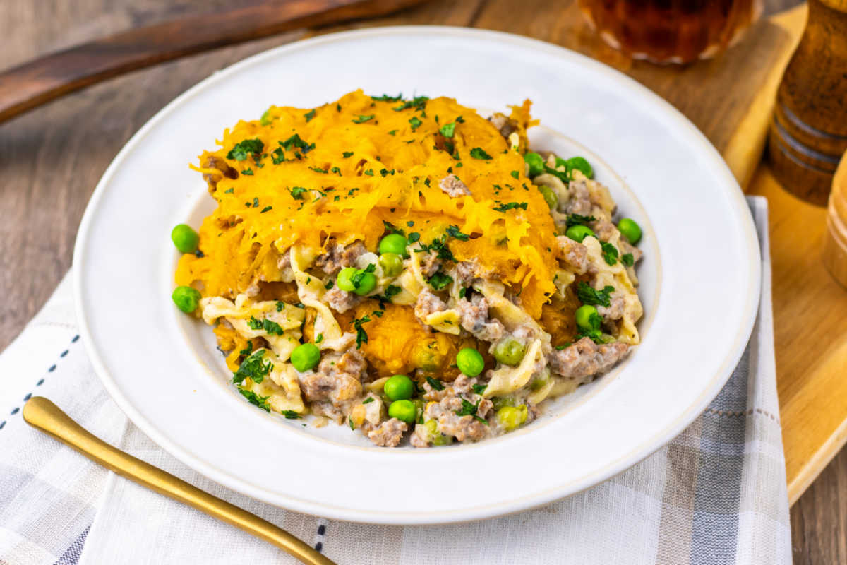 Amish Country Casserole 6 Serving of casserole with ground beef, peas, and egg noodles in creamy sauce with melted cheese on top, ready to eat.