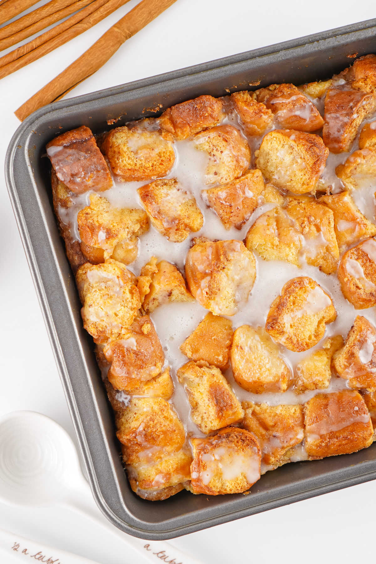 Donut Bread Pudding 8 Square baking dish filled with freshly baked donut bread pudding topped with a powdered sugar glaze, ready to be served.