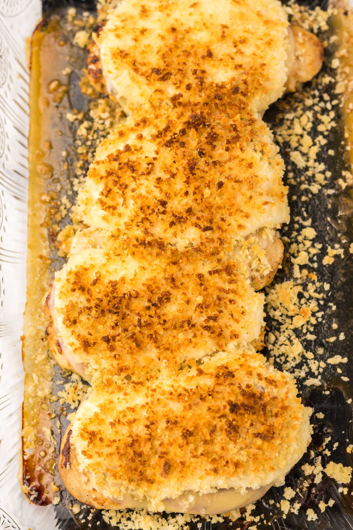 Glass baking dish filled with chicken breasts topped with melted cheese, parmesan ranch mixture and golden brown bread crumbs, ready to be served. 
