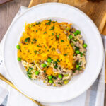 Plate of amish country casserole with egg noodles in cream of mushroom sauce with ground beef and peas with melted cheese over everything.
