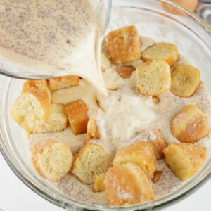 Donut Bread Pudding 12 Pouring custard mixture over bowl of donut chunks.