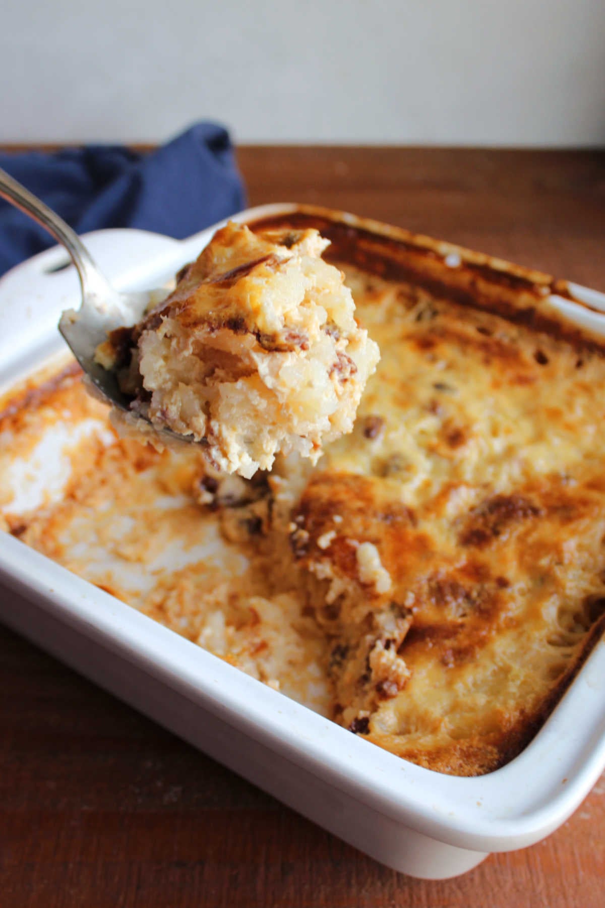 Baked Rice Pudding With Uncooked Rice 8 Vintage serving spoon getting a scoop of rice pudding out of the baking dish, showing its thick texture and caramlized top.