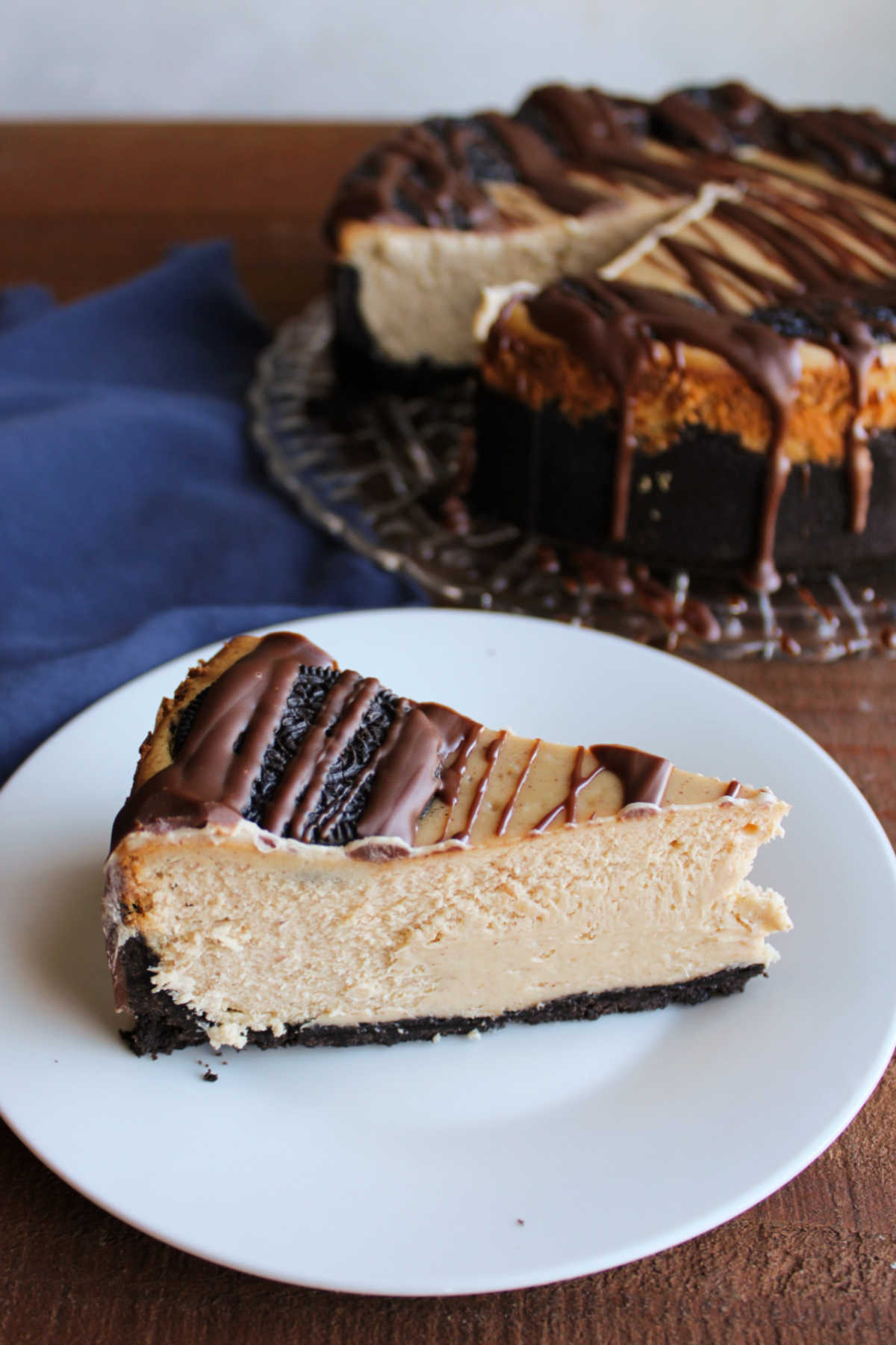 Slice of peanut butter Oreo cheesecake on plate showing smooth and creamy peanut butter cheesecake texture. 
