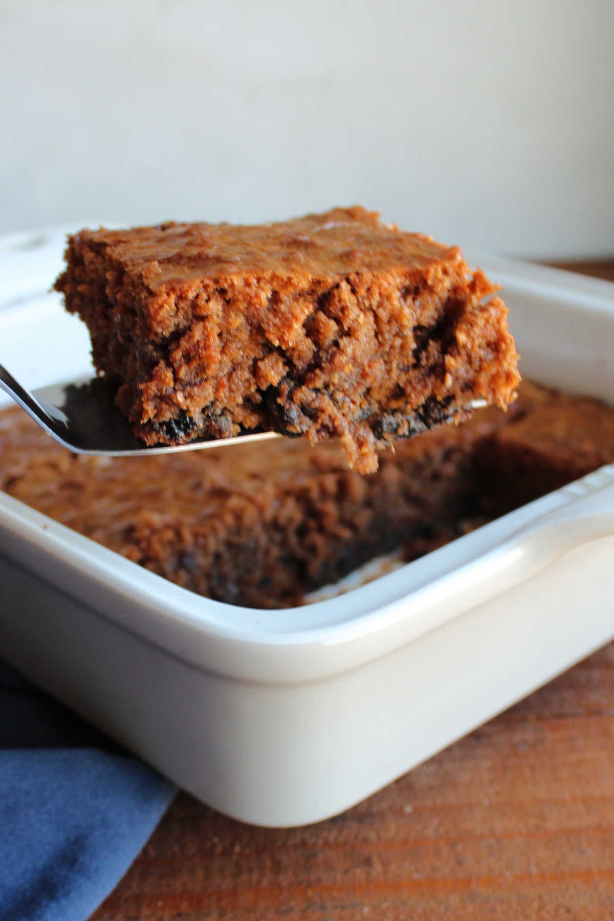 Spatula lifting a prune brownie out of the pan showing the fudgy texture with little bits of prunes. 
