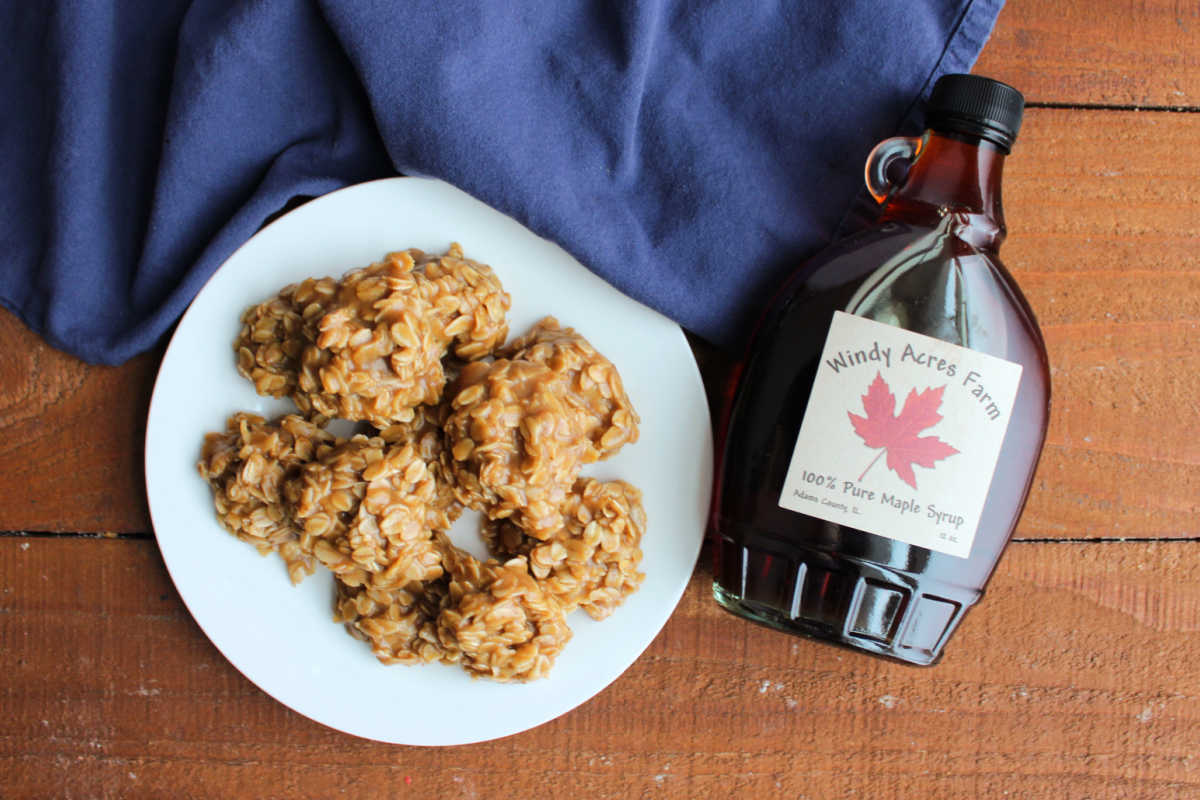 Plate of no bake cookies with maple syrup and oatmeal ready to eat next to a jar of pure maple syrup. 
