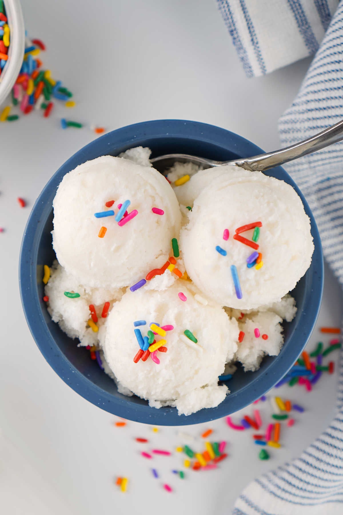 Scoops of snow ice cream in a bowl, topped with colorful sprinkles. 