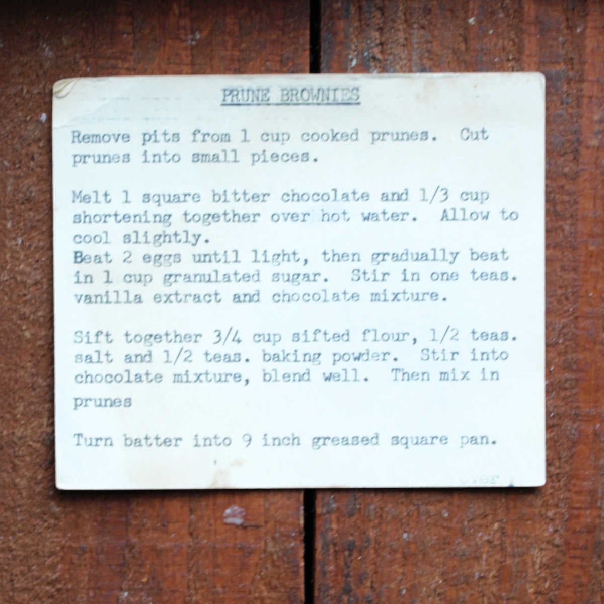 Browned index card with typewritten recipe for prune brownies on it. 