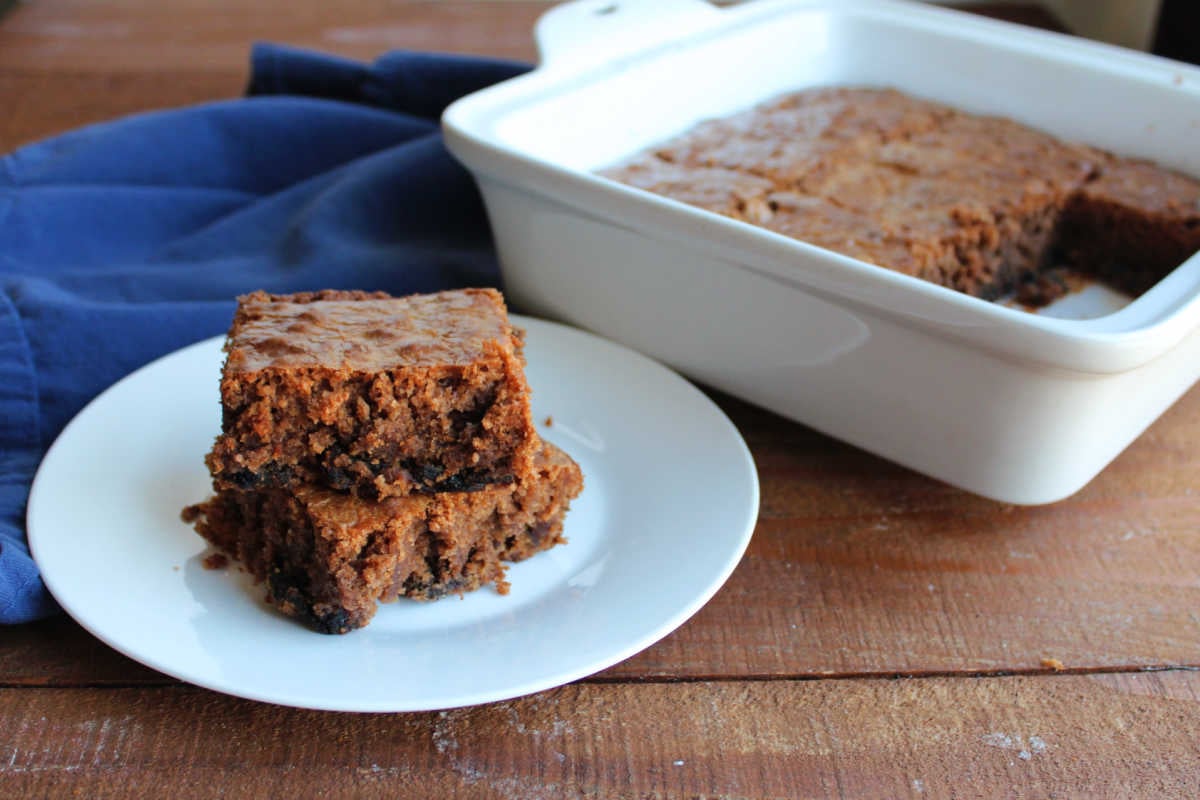Plate with pieces of prune brownies next to the pan with more brownies inside. 