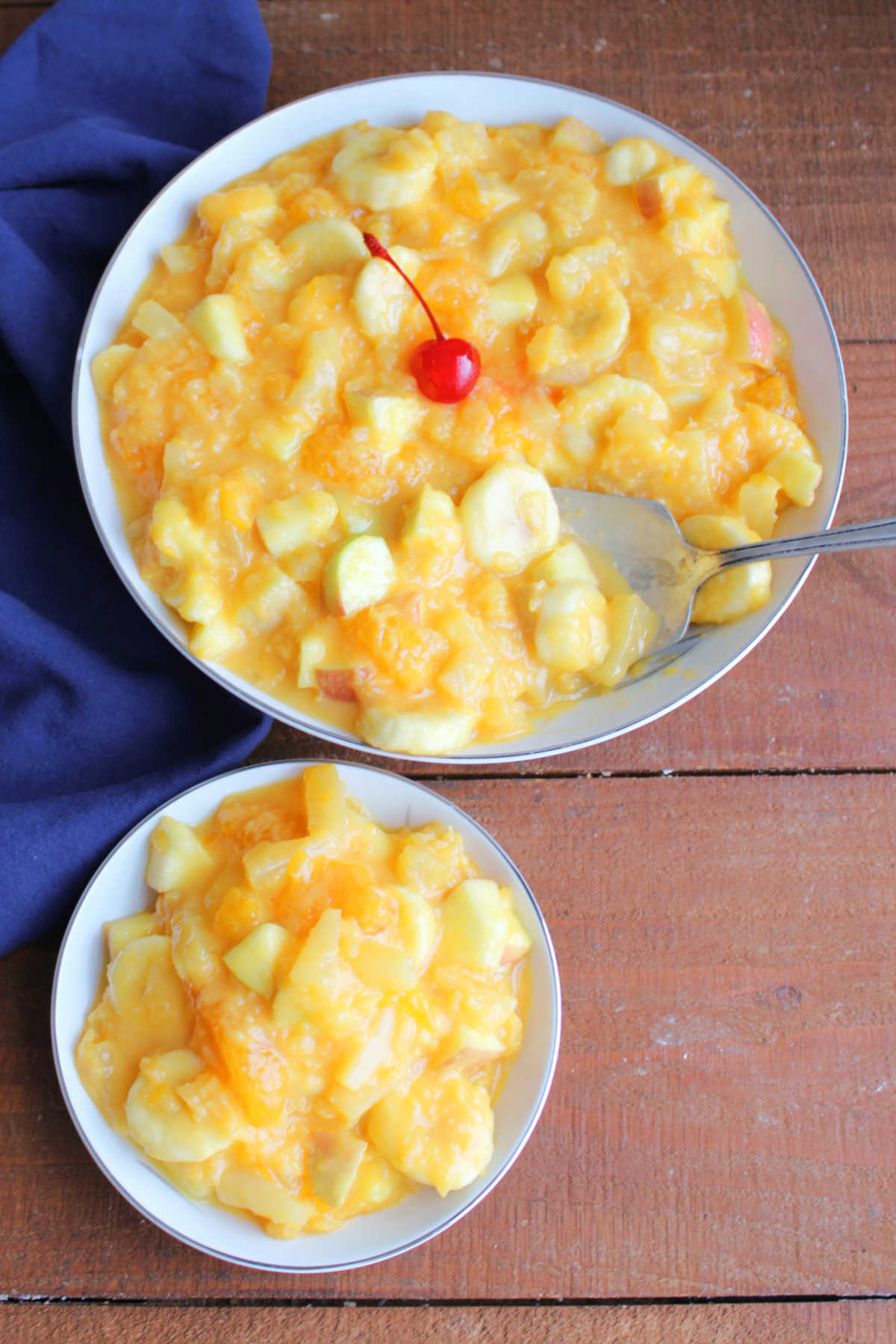 Tang Fruit Salad 9 Serving bowl of fruit salad with creamy orange dressing next to a smaller bowl with a serving of Tang fruit salad inside.