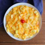 Bowl of fruit salad with bananas, apples, mandarin oranges, and pineapple in a creamy orange Tang dressing.