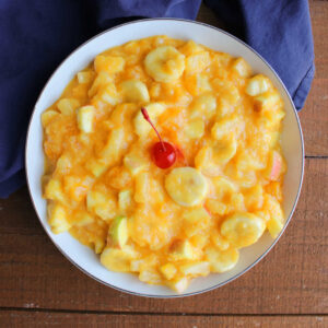 Tang Fruit Salad 11 Bowl of fruit salad with bananas, apples, mandarin oranges, and pineapple in a creamy orange Tang dressing.