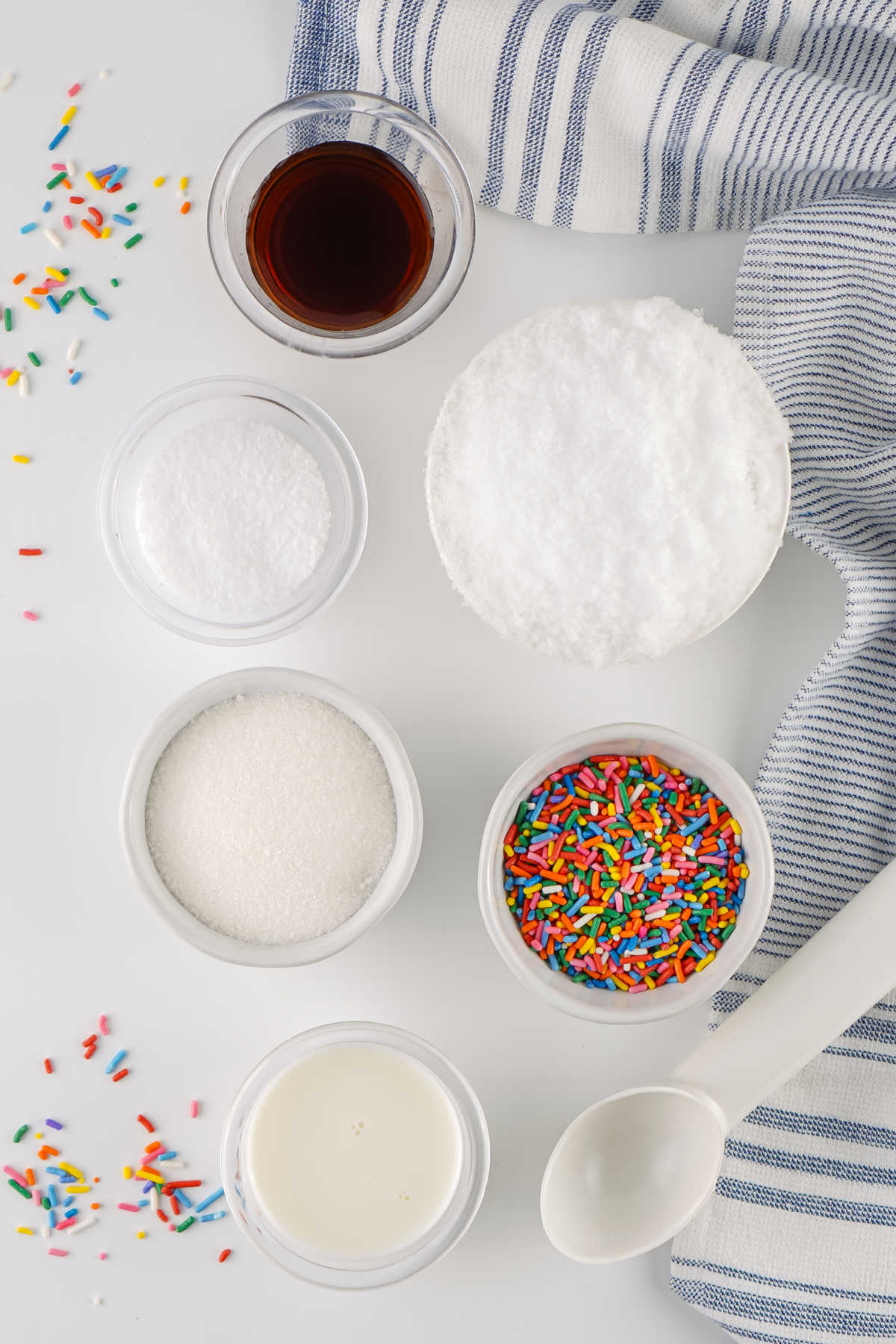 Ingredients including fresh snow, milk, sugar, vanilla, salt and sprinkles ready to be made into snow ice cream. 